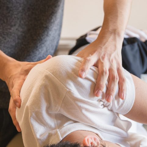 Man helping another man with shoulder pain